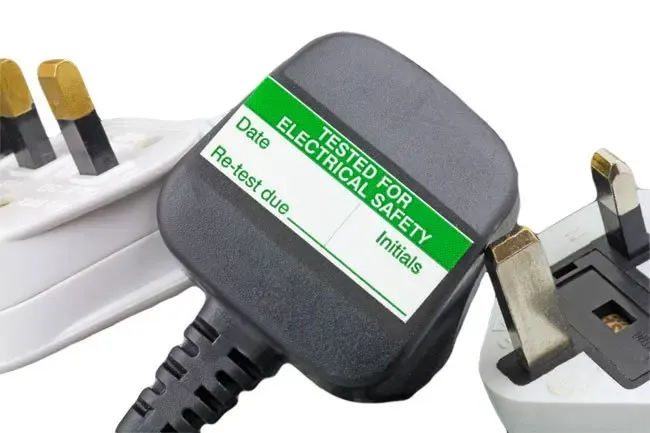 Appliance plug carrying a green 'Tested for electrical safety' label with test and re-test dates